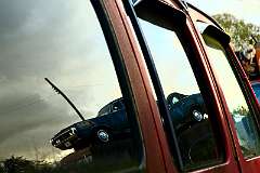 car reflected in another cars window in a breakers yard